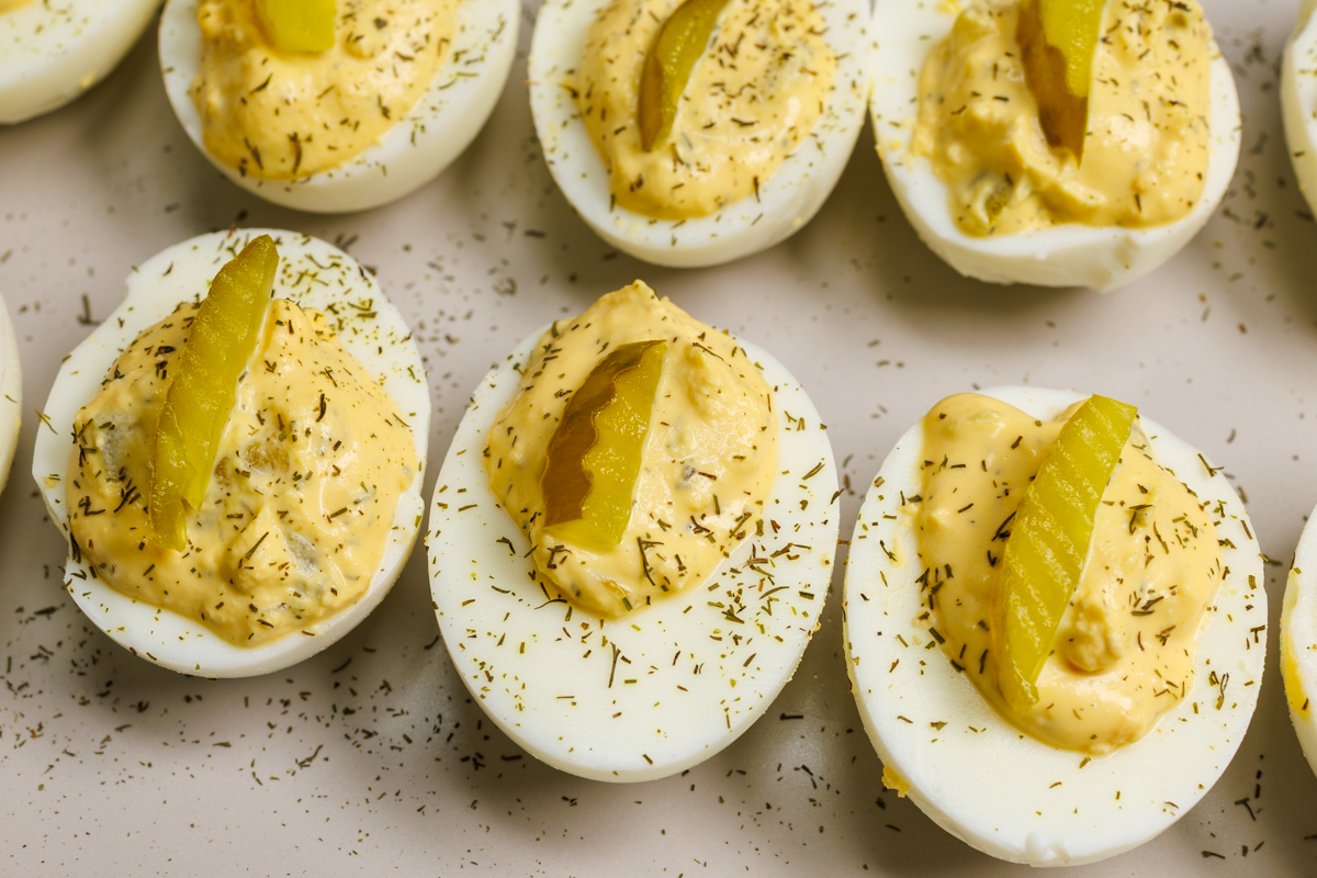 Dill pickle deviled eggs on a light gray plate.