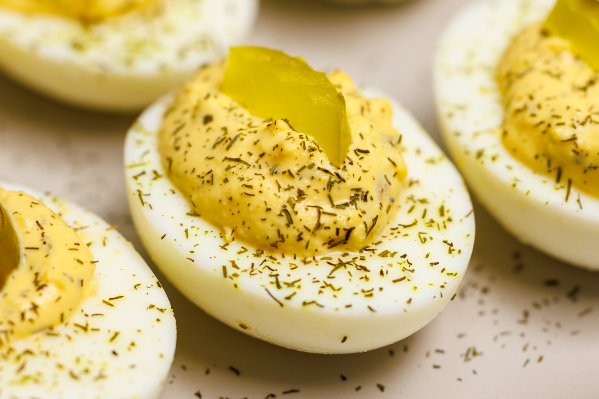 Dill pickle deviled eggs topped with dill pickle chip slices and sprinkled with dried dill.
