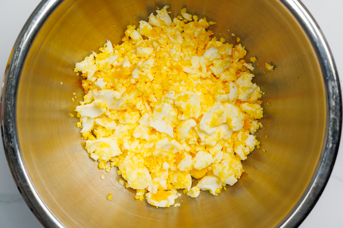 Chopped hard boiled eggs in a silver mixing bowl.